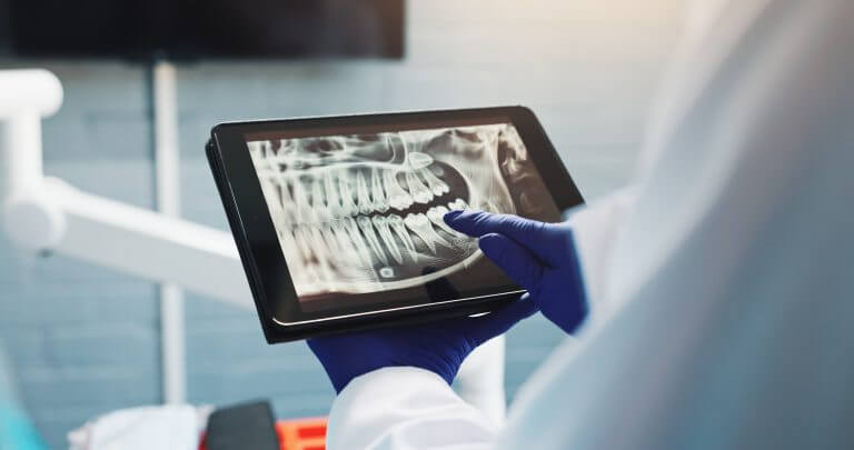 Zahnarzt betrachtet Röntgenbild auf Tablet
